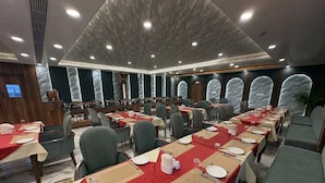 A conference room with long tables set for dining, equipped with nameplates, cutlery, and glassware. - Hotel Jyoti International (Bodh Gaya)
