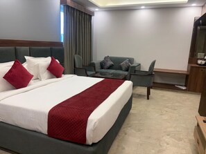A hotel room with a large bed, a sofa, a chair, and a small table.