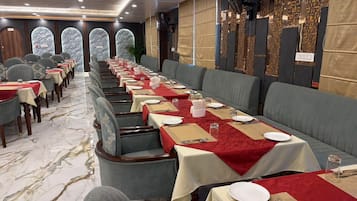 Un restaurante con mesas largas, manteles rojos y asientos tapizados en gris.