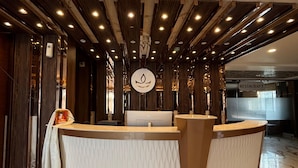 A reception desk with a marble floor, wooden paneling, and a sign indicating a restaurant. - Hotel Jyoti International (Bodh Gaya)