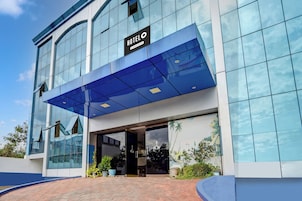 A modern hotel building with a glass facade and a blue awning.