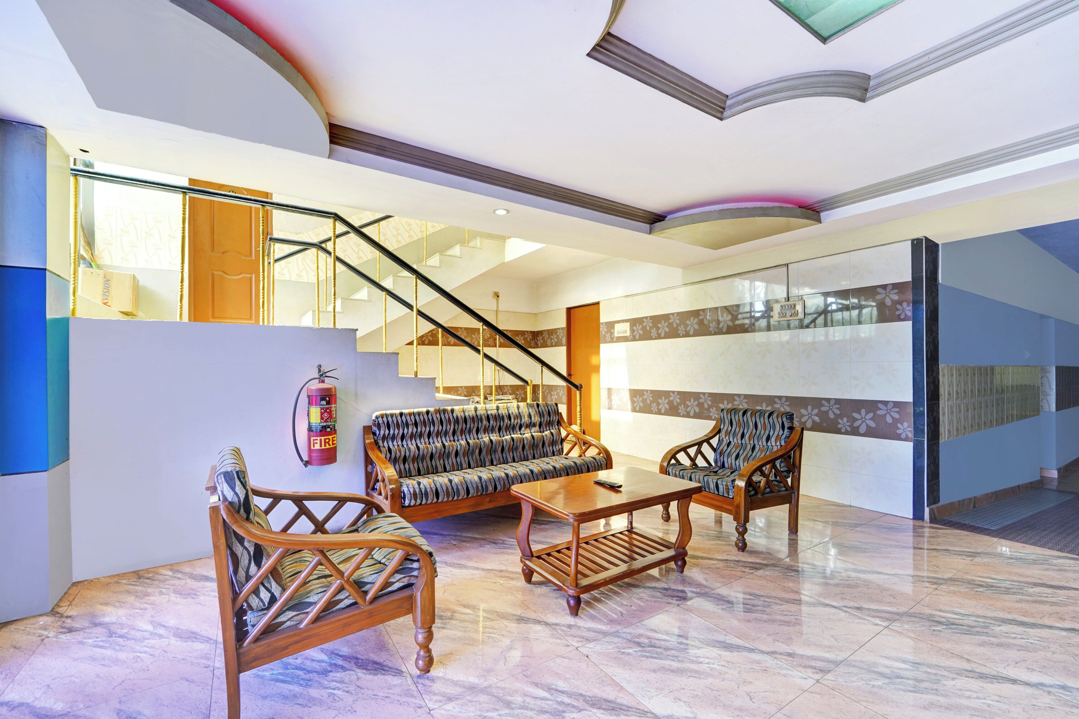 A spacious lobby with a staircase, seating area, and a fire extinguisher.