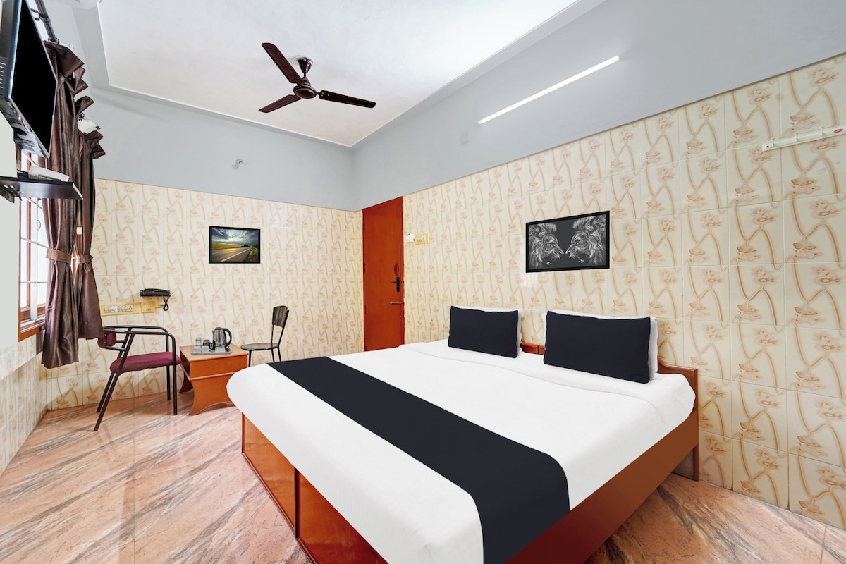 Una habitación de hotel con cama, escritorio, silla, ventilador de techo y ventana con cortinas.