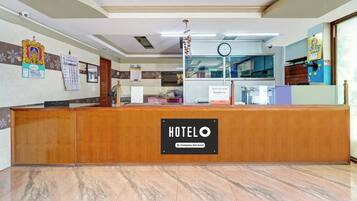 Una recepción de hotel con un letrero que dice 'HOTELO', un reloj y un calendario en la pared.