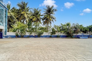 Un patio empedrado con palmeras y un edificio de paredes azules y blancas.