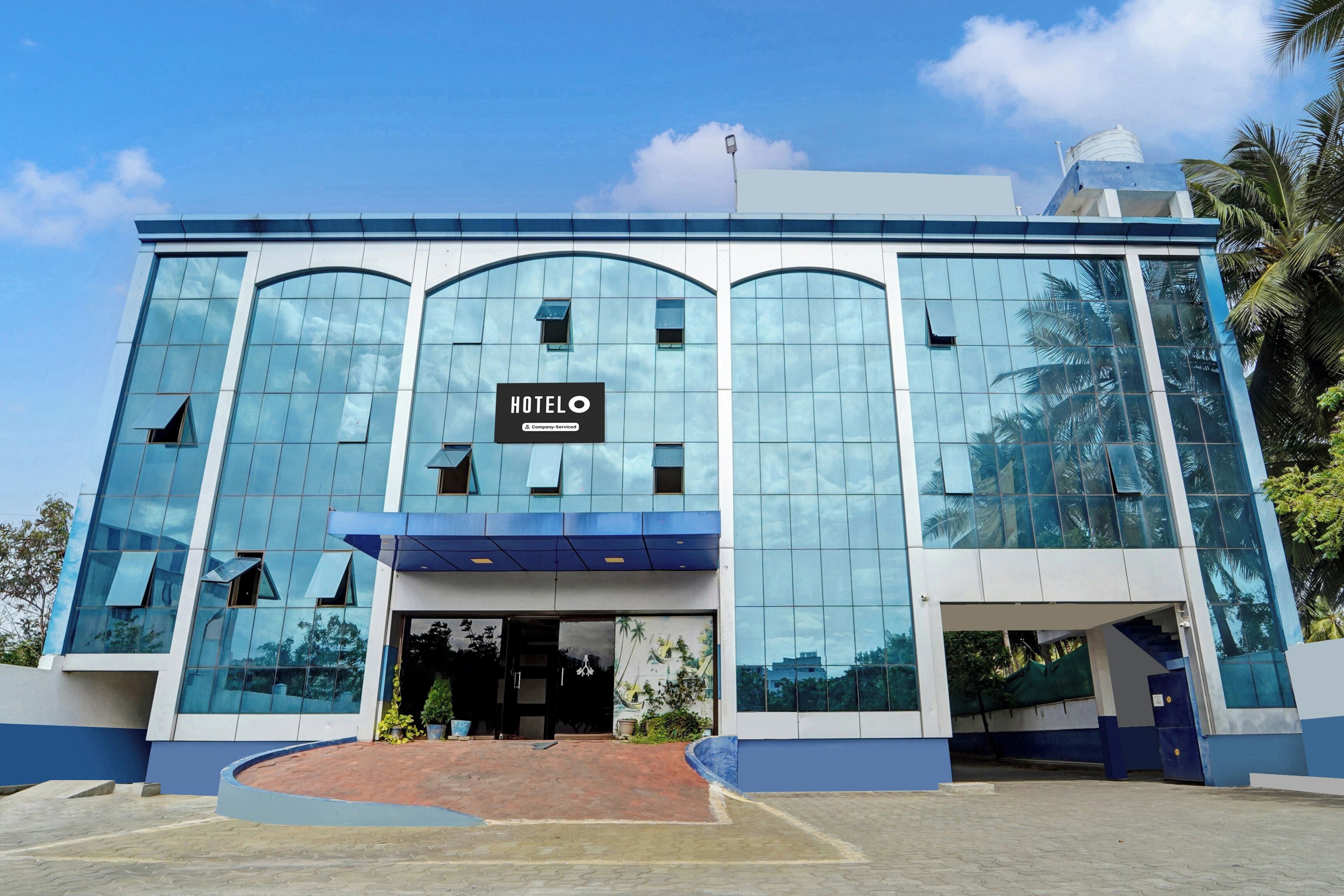 A modern hotel building with a glass facade, a prominent 'HOTEL O' sign, and a blue entrance.