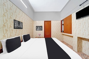 Quarto de hotel com cama grande, televisão de tela plana fixada na parede e porta de madeira.