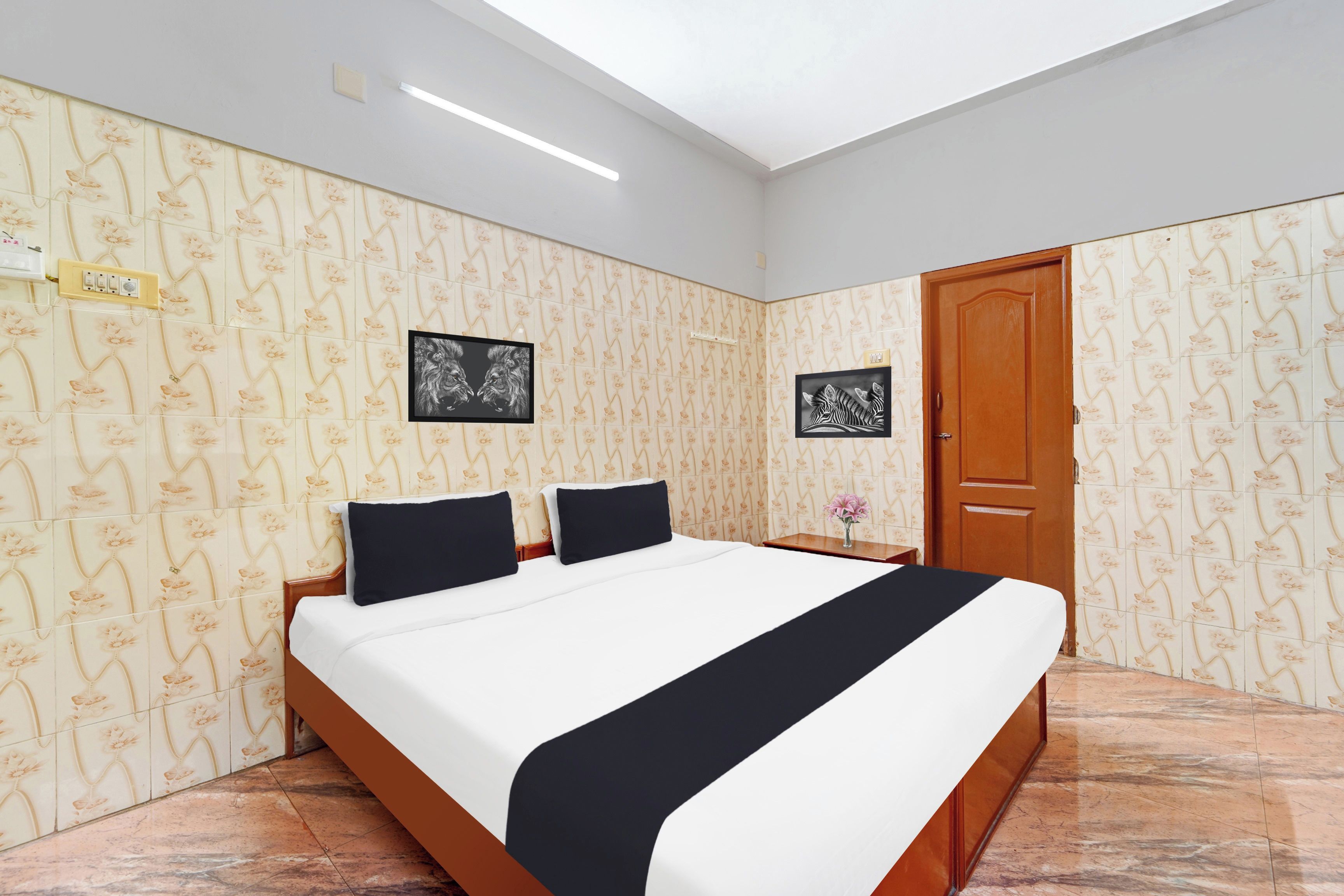 A hotel room with a bed, two nightstands, a wooden door, and floral wallpaper.