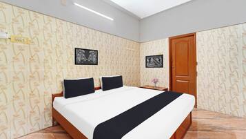 A hotel room with a bed, two nightstands, a wooden door, and floral wallpaper.