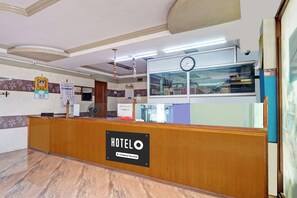 Mostrador de recepción de hotel con un reloj, un calendario y un cartel que indica que es un hotel de servicios para empresas.