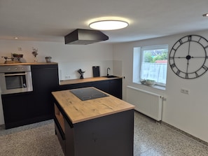 A modern kitchen with a built-in oven, a sink, and a wooden countertop. - Charmante Auszeit im historischen Fachwerkhaus (Rheinau)