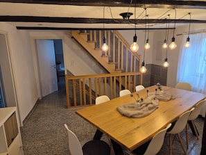 A dining area with a wooden table, white chairs, and a staircase. - Charmante Auszeit im historischen Fachwerkhaus (Rheinau)