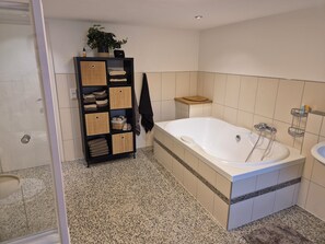 A bathroom with a freestanding bathtub, a shelf with folded towels, and a potted plant. - Charmante Auszeit im historischen Fachwerkhaus (Rheinau)