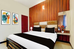 Ein Hotelzimmer mit einem großen Bett, einer Wand mit Holzvertäfelung, einer roten Tür und zwei gerahmten Kunstwerken an der Wand.