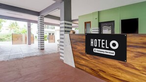 A hotel reception area with a 'HOTEL' sign, a company-serviced label, and a view of the outdoor area. - Hotel O Singanallur Railway Junction (Coimbatore)