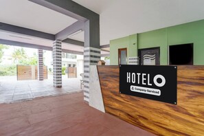 Ein Hotelrezeptionsbereich mit einem 'HOTEL'-Schild, einer Kennzeichnung für Firmenkunden und Blick auf den Außenbereich.