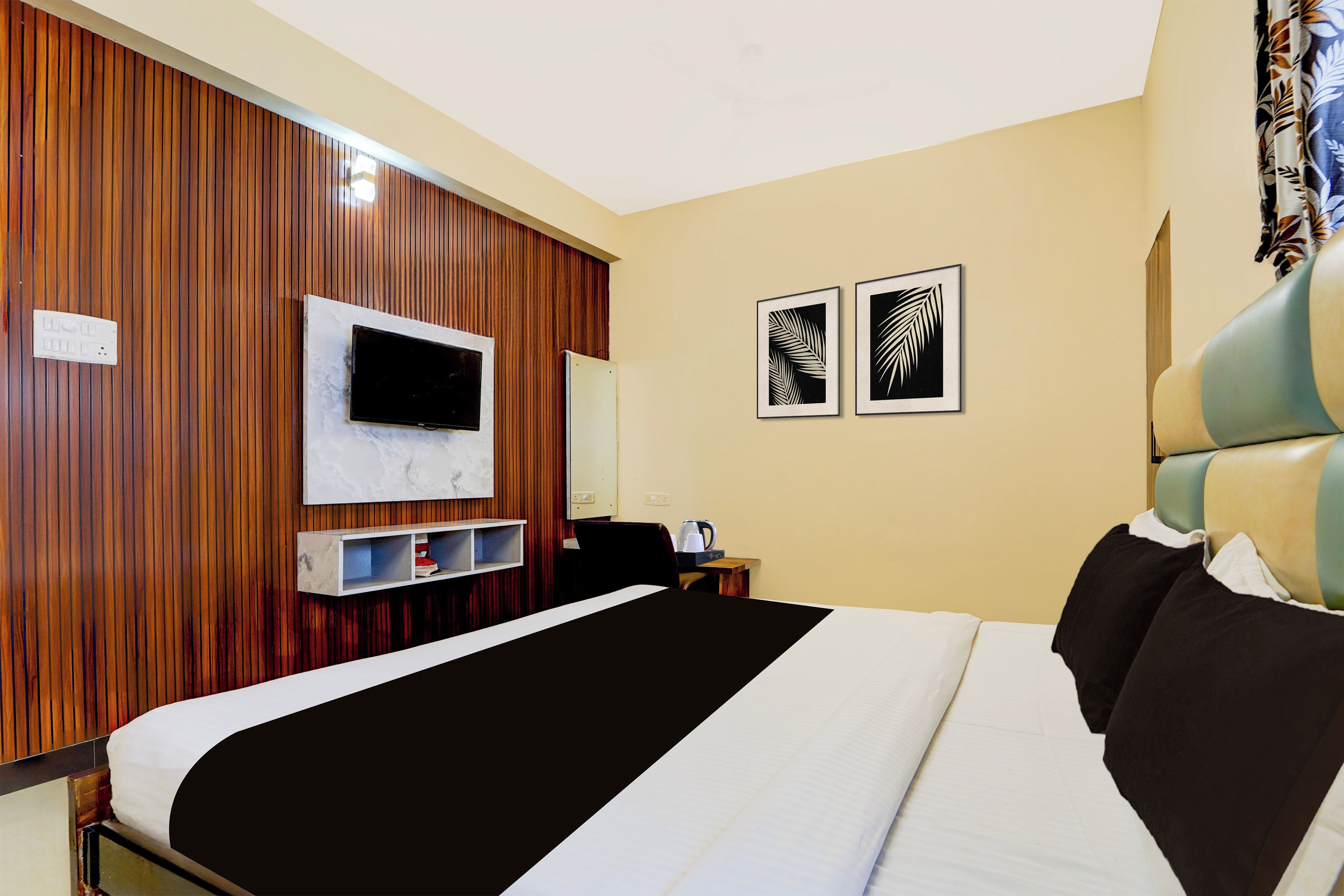 Ein Hotelzimmer mit einem Bett, einem Fernseher, einem Schreibtisch und zwei gerahmten Bildern an der Wand.