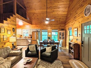 Interior acollidor d'una cabana amb zona de menjador, cuina i espai per seure.