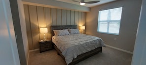 Quarto com uma cama, duas mesas de cabeceira com abajures, um ventilador de teto e uma janela com persianas.