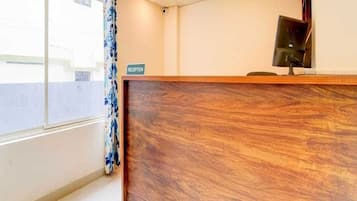 A reception desk with a sign, a window with curtains, and a ceiling with recessed lighting.