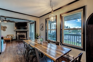 A spacious dining area with a long wooden table, black chairs, and a view of the outside through large windows. - Newly Renovated Beech Mountain Bliss; Be close to all the action (Beech Mountain)