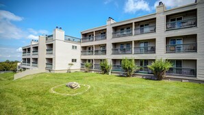Um edifício residencial de vários andares com um jardim bem cuidado e um elemento decorativo circular em pedra.