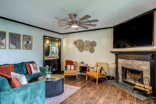 A living room with a fireplace, a ceiling fan, and a large TV. - Newly Renovated Beech Mountain Bliss; Be close to all the action (Beech Mountain)