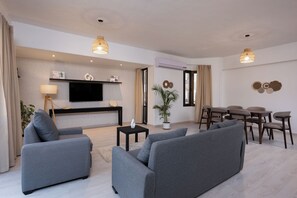 A modern living room with grey sofas, a flat-screen TV, a dining area with a table and chairs, and a potted plant. - perfect stay at Mexican by Spacey #12 (cairo)