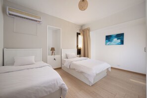 A hotel room with two beds, a ceiling fan, an air conditioning unit, a painting, and a wooden floor. - perfect stay at Mexican by Spacey #12 (cairo)