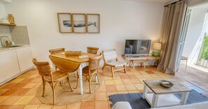 A dining area with a table and chairs, a television, and a kitchen area with a sink and cabinets. - Rustic-modern style apartment with sea views (Calella de Palafrugell)