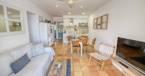 A living room with a sofa, chairs, a TV, and a kitchen in the background. - Rustic-modern style apartment with sea views (Calella de Palafrugell)