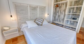 A bedroom with a bed, a bedside table, a lamp, and a wardrobe. - Rustic-modern style apartment with sea views (Calella de Palafrugell)