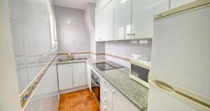 Eine Küche mit weißen Schränken, einer Granitabdeckung und einem eingebauten Backofen.