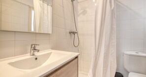 A bathroom with a white sink, a mirror, a shower with a curtain, and a toilet. - Three bedroom apartment with sea view (Calella de Palafrugell)