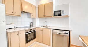A compact kitchen with a built-in oven, a microwave, and a dishwasher. - Three bedroom apartment with sea view (Calella de Palafrugell)