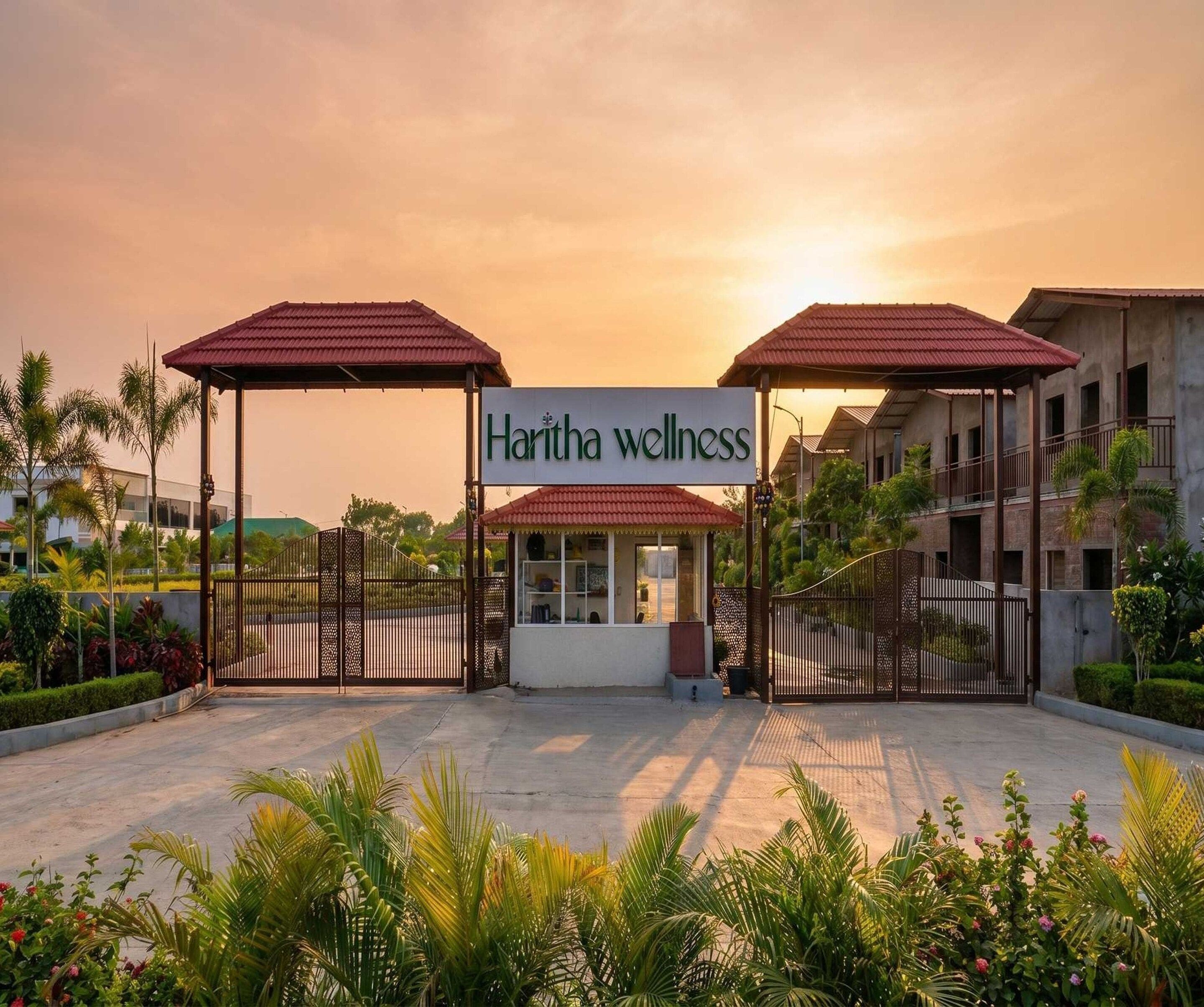 A wellness center named Haritha wellness with a covered entrance, a gated driveway, and surrounding greenery.