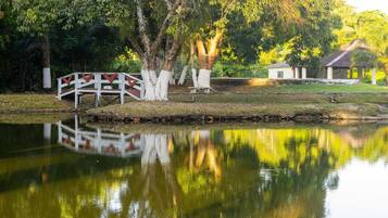 Um lago calmo com uma ponte de madeira e um pequeno edifício ao fundo.