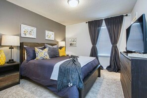 A bedroom with a bed, bedside tables, a dresser, and a television. - 5BR Mario-themed home near Disney | Pool & Spa (Kissimmee)
