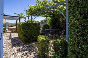 A garden with a pergola, a table and chairs, and a stone pathway. - Charming house with a pool, magnificent views of the valley and Beynac Castle (Beynac-et-Cazenac)