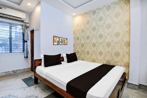 A hotel room with a bed, a window with curtains, a wall with a floral pattern, and a ceiling with recessed lighting. - Hotel O Botanical Garden  (Howrah)
