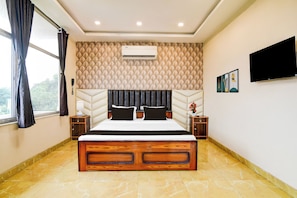 Habitación de hotel con cama, televisión, aire acondicionado de pared y ventana con cortinas.