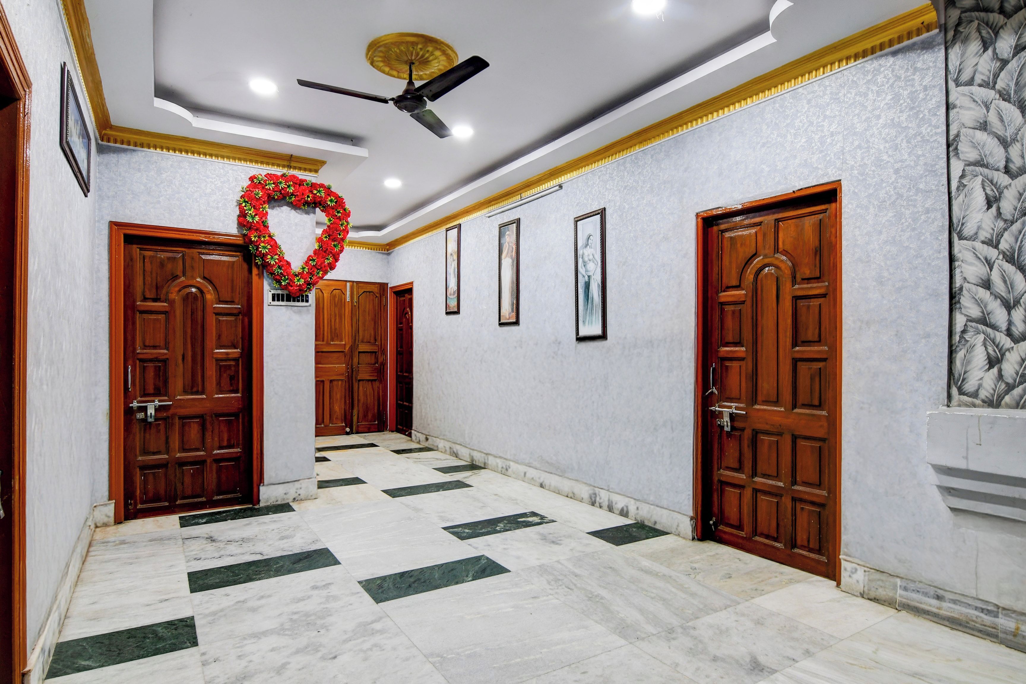 A hallway with marble flooring, wooden doors, and a ceiling fan.