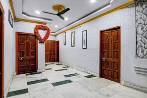 Un couloir doté d’un sol en marbre, de portes en bois et d’un ventilateur de plafond.