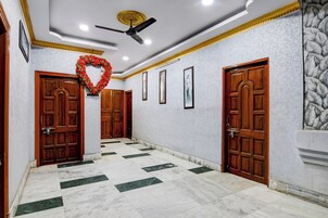 A hallway with marble flooring, wooden doors, and a ceiling fan.