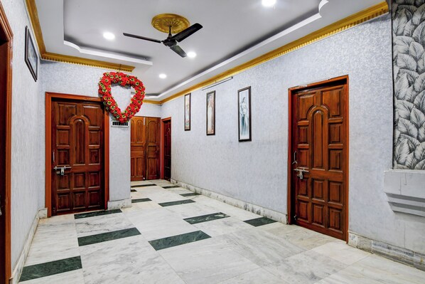 A hallway with marble flooring, wooden doors, and a ceiling fan.