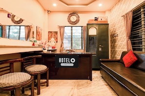 Un vestíbulo de hotel con mostrador de recepción, zona de estar y detalles decorativos.