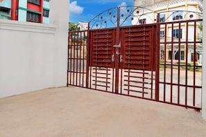 A gated entrance with a metal gate and a white wall. - Hotel O Botanical Garden  (Howrah)