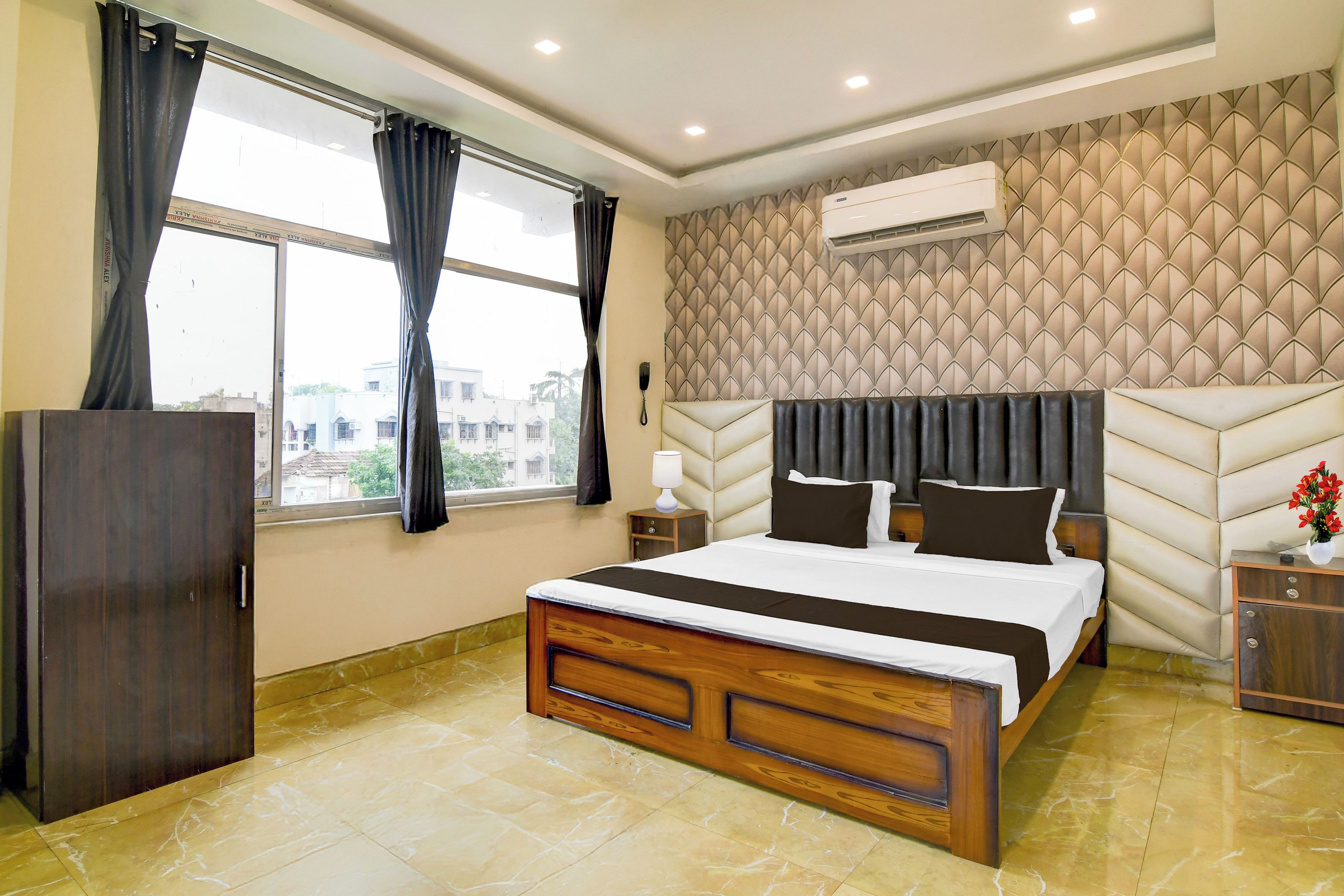 Habitación de hotel con cama, armario, mesita de noche, aire acondicionado y ventana con cortinas.