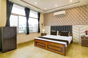 Habitación de hotel con cama, armario, mesita de noche, aire acondicionado y ventana con cortinas.