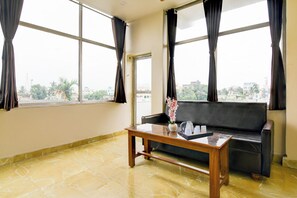 Una habitación con sofá, una mesita de centro y ventana con cortinas.
